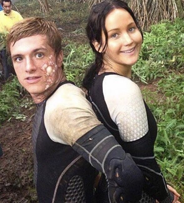 a man and woman with mud on their face standing in the woods, smiling at the camera