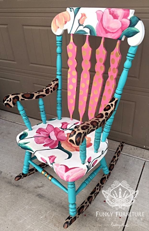 a painted rocking chair with pink flowers and leopard print on the back, sitting in front of a garage door