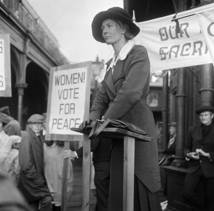 a woman standing in front of a crowd holding signs