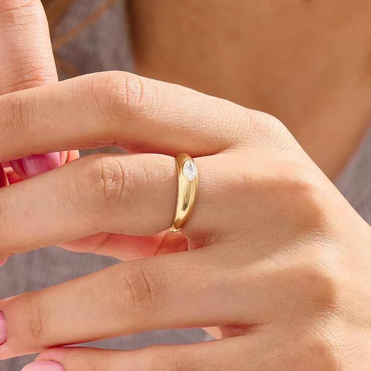 a woman's hand wearing a gold ring with a diamond in the middle,