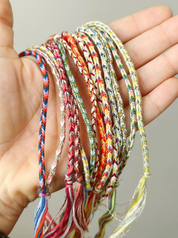 a person holding several different colored bracelets in their hand