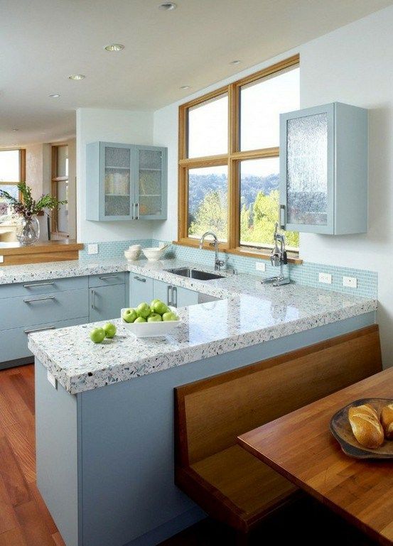 a large kitchen with blue cabinets and white counter tops, along with hardwood floors on both sides