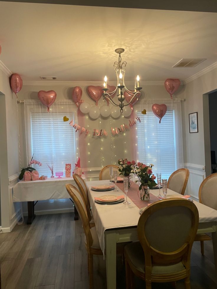 a dining room filled with lots of pink balloons and table set up for a party