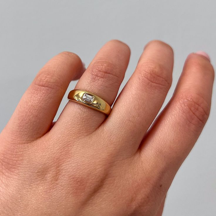 a person's hand with a gold ring on it and a diamond in the middle