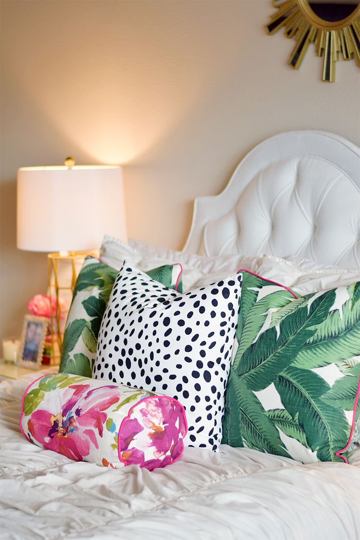 a white bed topped with lots of pillows next to a night stand and table lamp