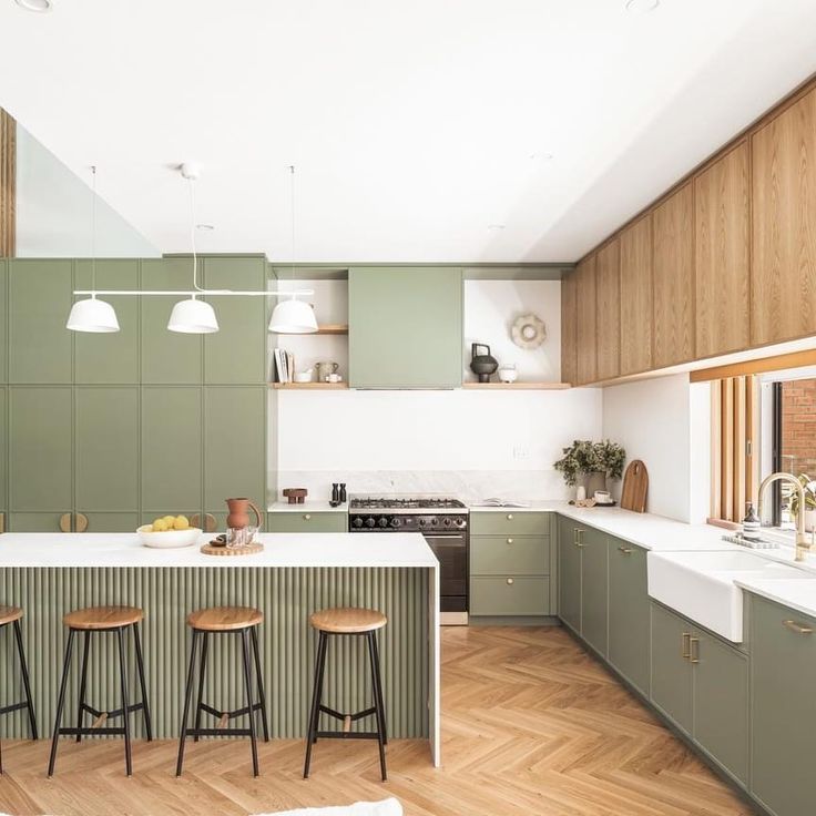 a kitchen with green cabinets and stools next to a stove top oven on a wooden floor