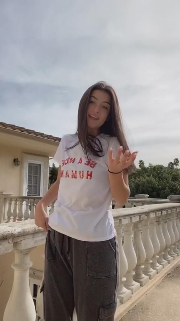 a woman is standing on a balcony with her hands in the air