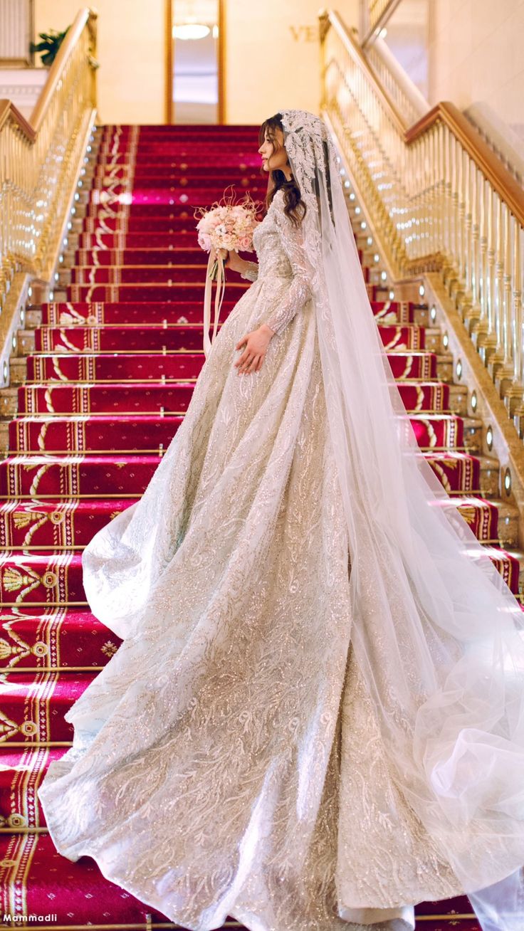 a woman in a wedding dress is standing on the stairs with her veil blowing back