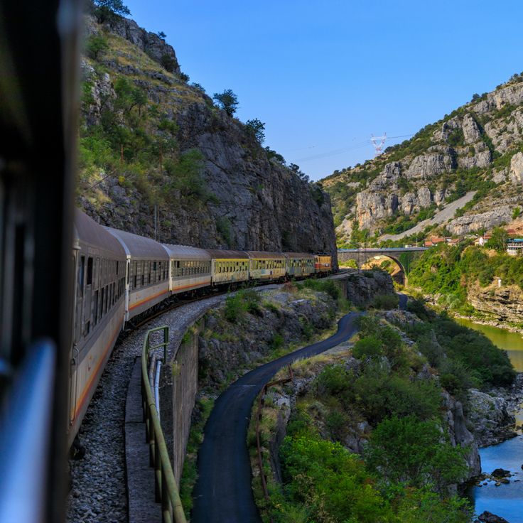 a train traveling down tracks next to a river