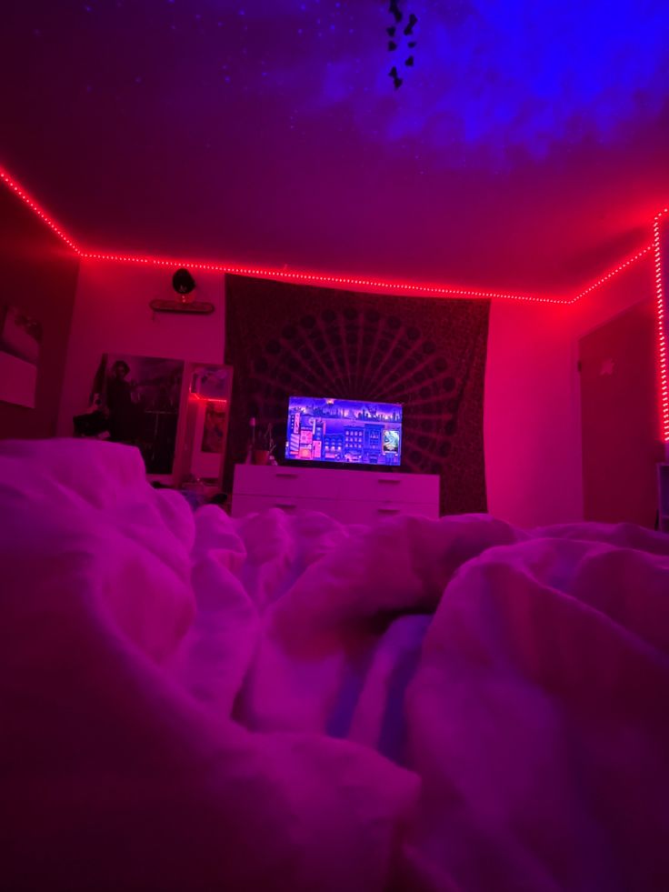 there is a television in the room with red lights on it and purple light coming from the ceiling