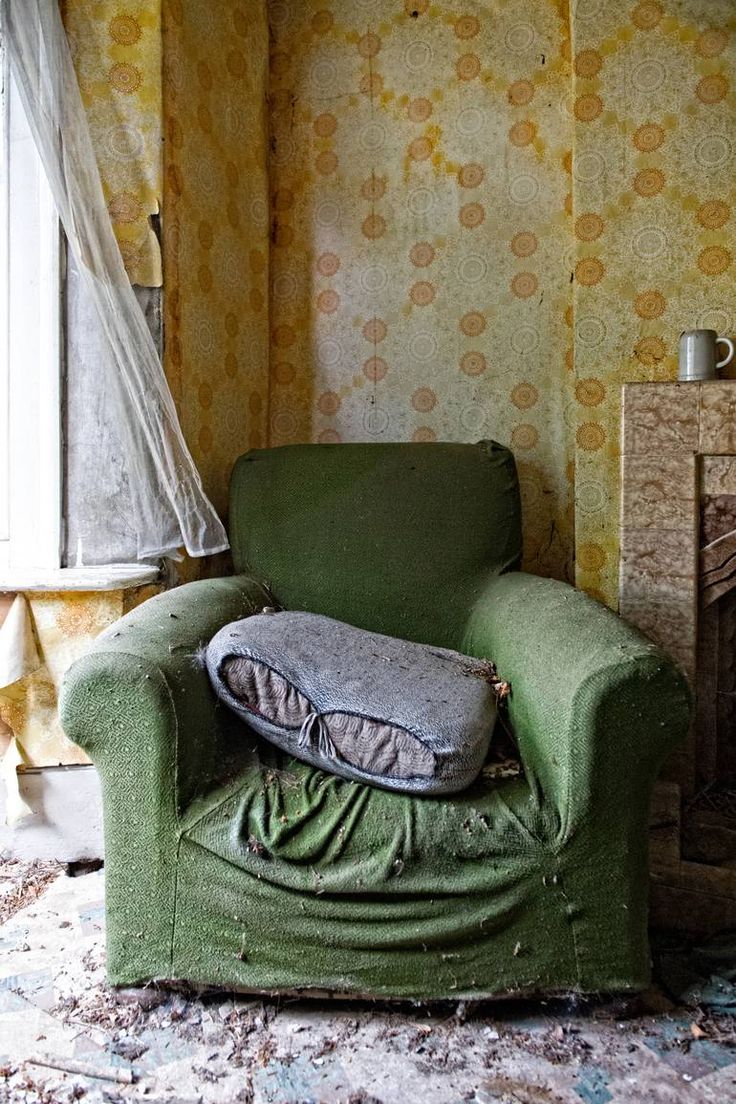 a green chair sitting in front of a window next to a fire place with a pillow on top of it