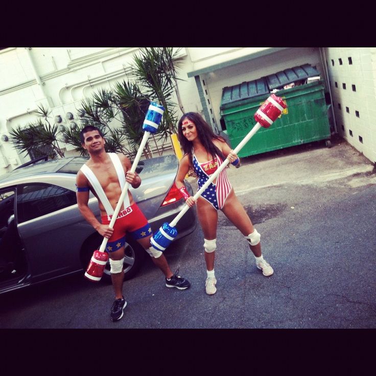 two people dressed in patriotic outfits holding american flags and toothbrushes while standing next to a car