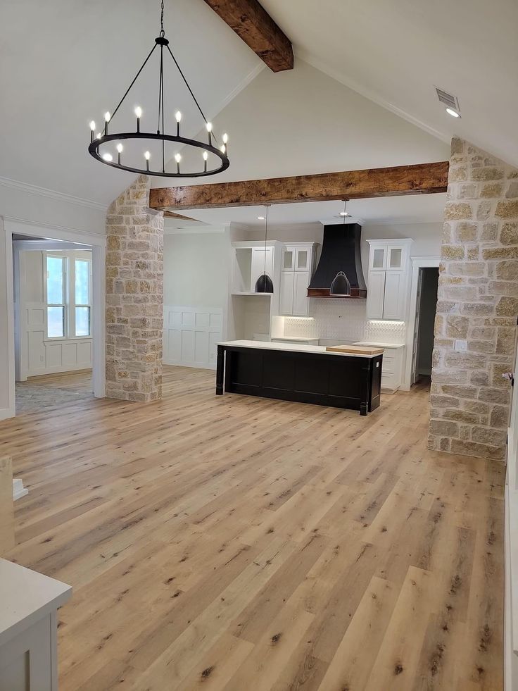 an empty kitchen and living room with exposed beams in the ceiling, wood flooring