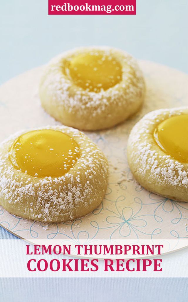 three lemon thumbprint cookies on a plate with powdered sugar and jelly in the middle