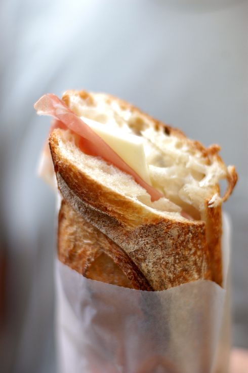 a close up of a sandwich in a wrapper with meat and cheese on it