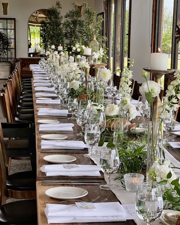 a long table is set up with white flowers and greenery for an elegant dinner