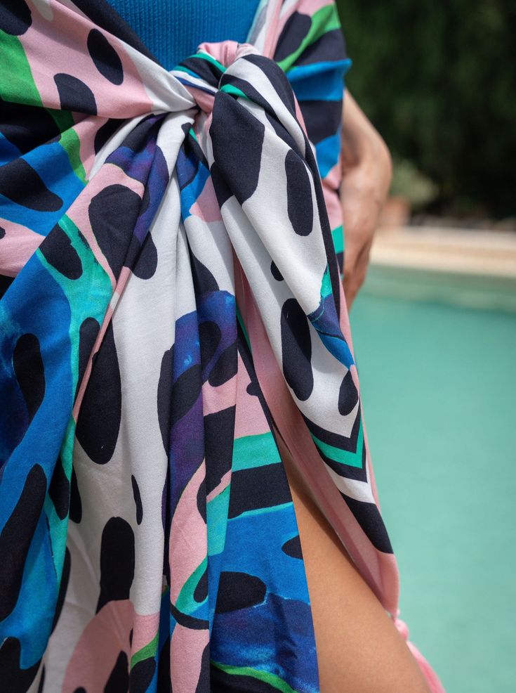 Meet the Melanie Pareo, your go-to layer for beach days and poolside lounging. Generously sized and crafted from soft, breathable rayon, it’s easy to tie and re-tie as you move from sun to shade. Wear it as a sarong skirt, knot it as a chic cover-up, or wrap it around your waist—this versatile pareo is designed for wherever the day takes you. Finished with tassel trim for a touch of movement, it’s a must-have for every woman who’s in and out of the water and always on the go.Pairs perfectly with Summer Tie-side Sarong For Poolside, Summer Sarong With Tie-side Bottom For Poolside, Summer Style Tie-side Sarong For Poolside, Summer Tie-side Bottom Sarong For Poolside, Casual Spring Pool Sarong, Tied Swimwear For Summer, Summer Pool Sarong With Tropical Print, Summer Pool Tropical Print Sarong, Multicolor Tie-back Swimwear For Beach