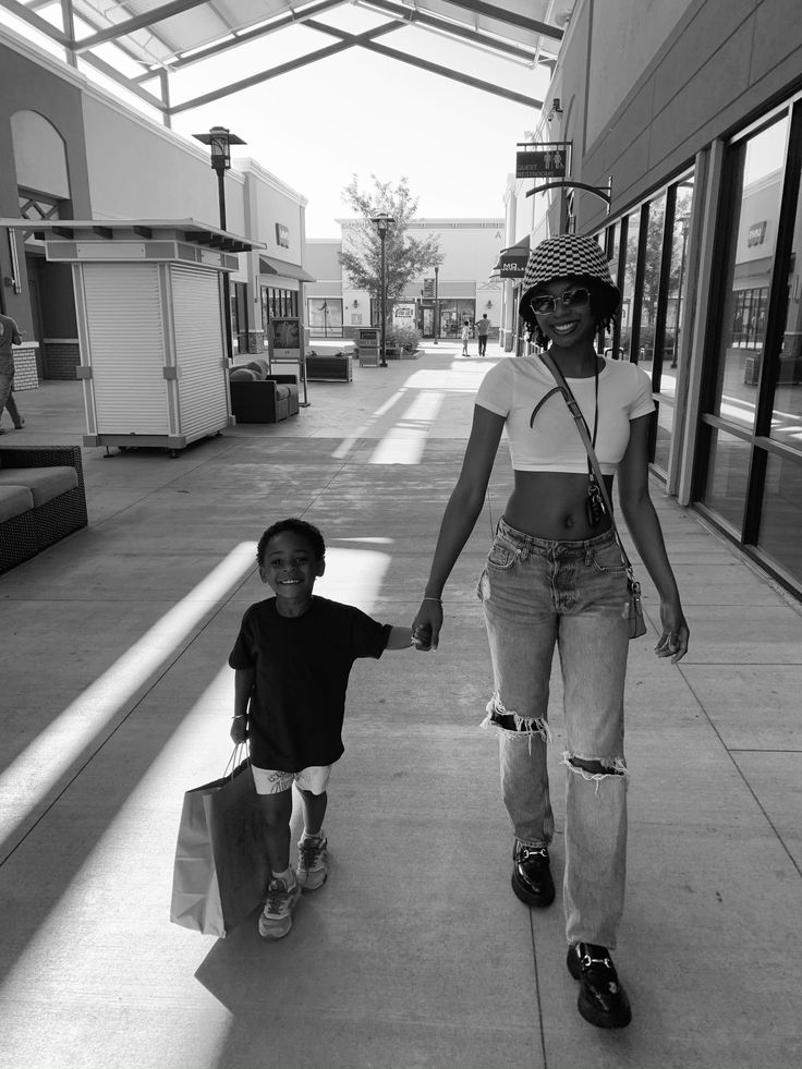 a woman walking down a sidewalk holding hands with a child