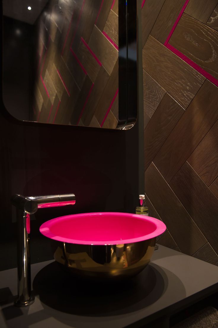 a pink bowl sitting on top of a counter in front of a wall mounted mirror