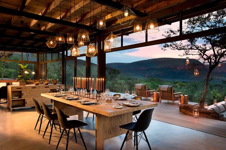 an outdoor dining area with wooden tables and chairs, overlooking the valley outside at dusk