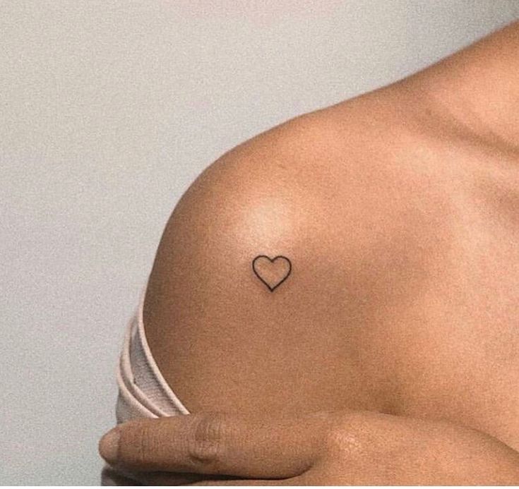 a woman with a small heart tattoo on her chest