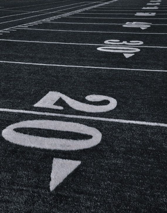 an empty football field with numbers and arrows painted on the sidelines in black and white