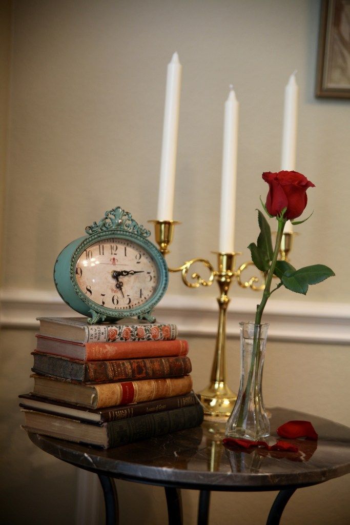 a table with books and a clock sitting on top of it next to a candle holder