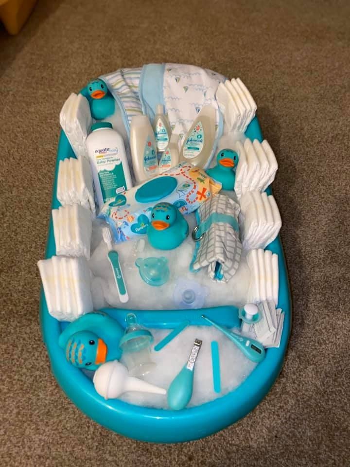 a blue and white baby bath tub filled with lots of hygiene items on top of a carpeted floor