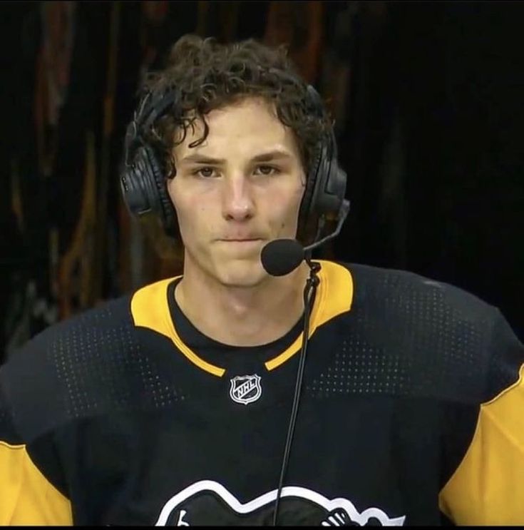 a hockey player wearing headphones while sitting in front of a microphone and looking at the camera