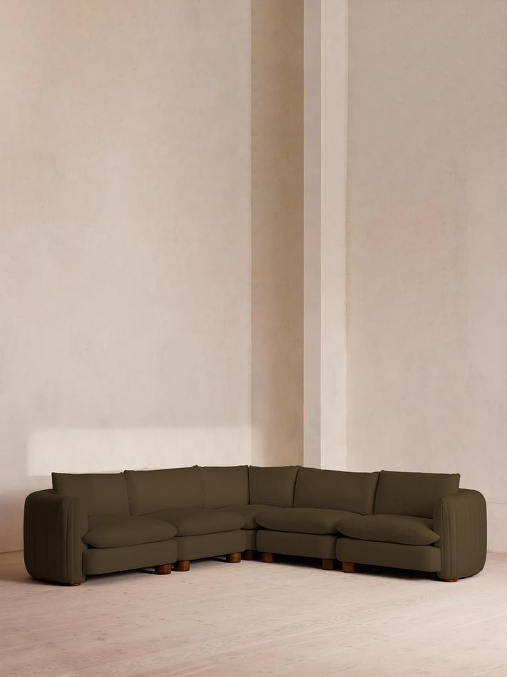 a large sectional couch sitting on top of a hard wood floor next to a white wall