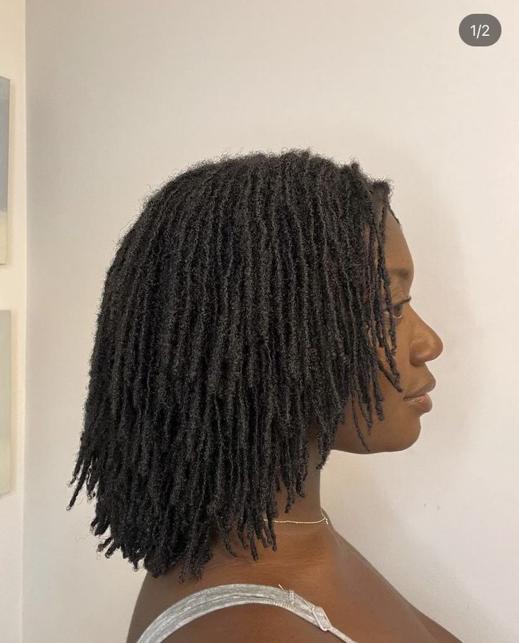 the back of a woman's head with long, curly hair in front of a white wall