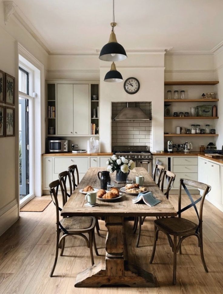 a dining room table with chairs and a clock on the wall in front of it