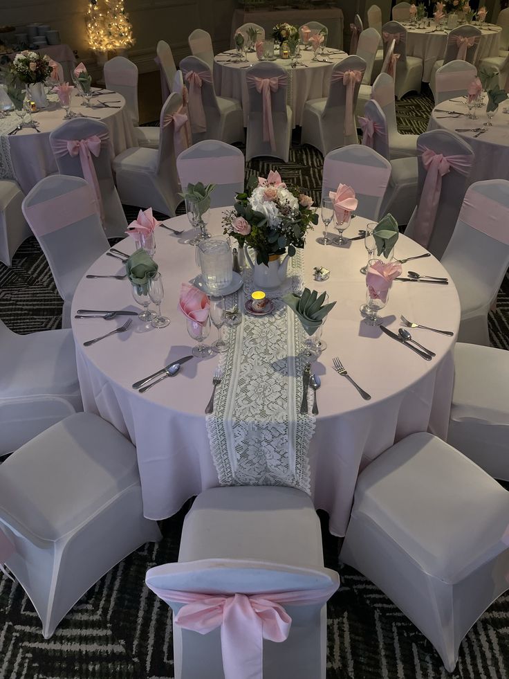 the tables are set with white chairs and pink sashes