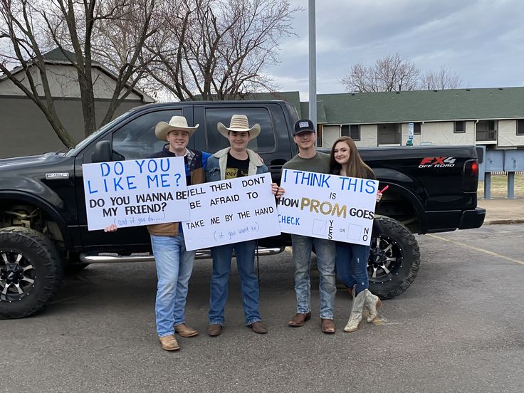 three men standing in front of a truck holding signs