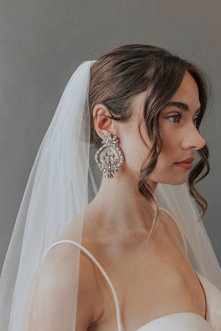 a woman wearing a wedding veil and earrings