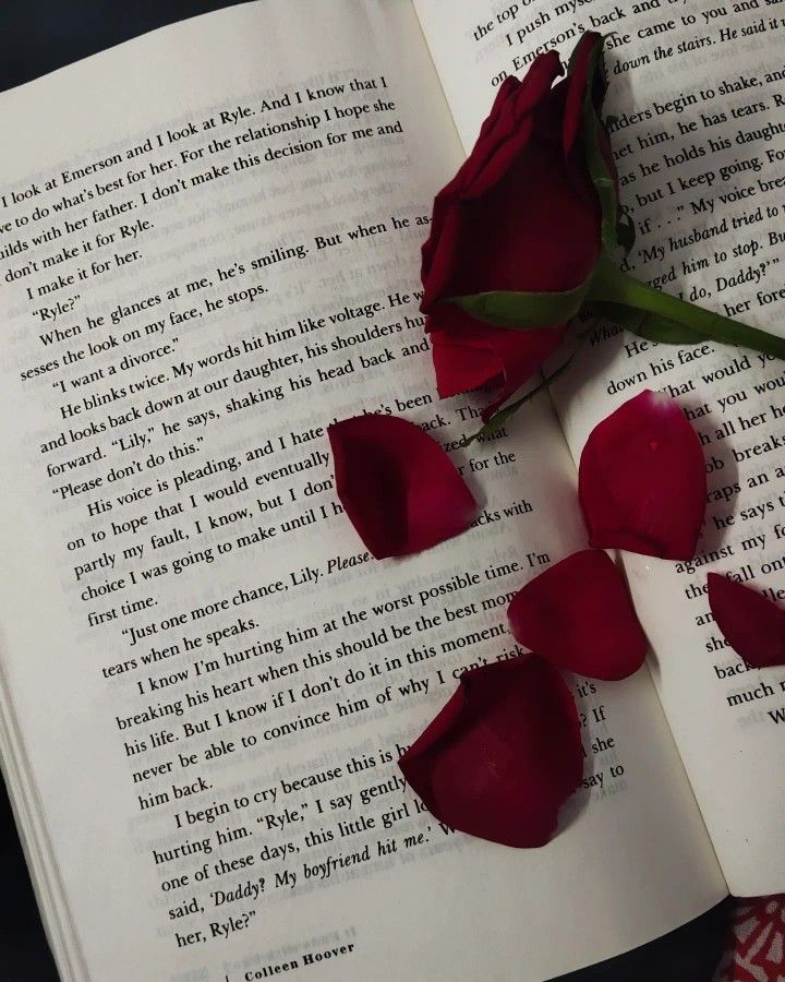 three red roses laying on top of an open book