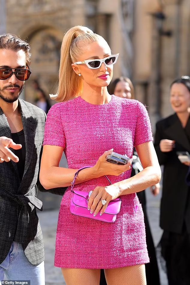 a woman in a pink dress standing next to a man wearing sunglasses and a suit