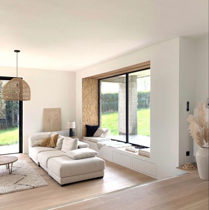 a modern living room with white furniture and large windows overlooking the grass covered field outside