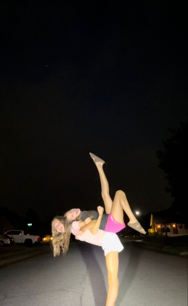 a woman is doing a handstand on her skateboard in the street at night