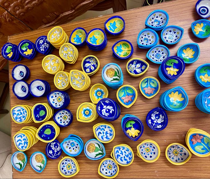 a wooden table topped with lots of blue and yellow plates on top of each other