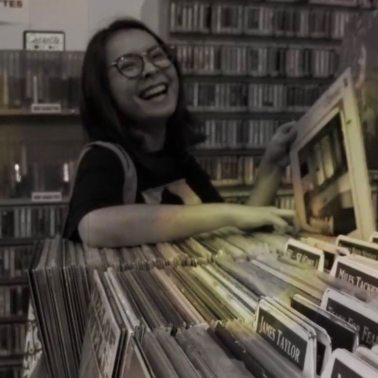 a woman is smiling while looking at records