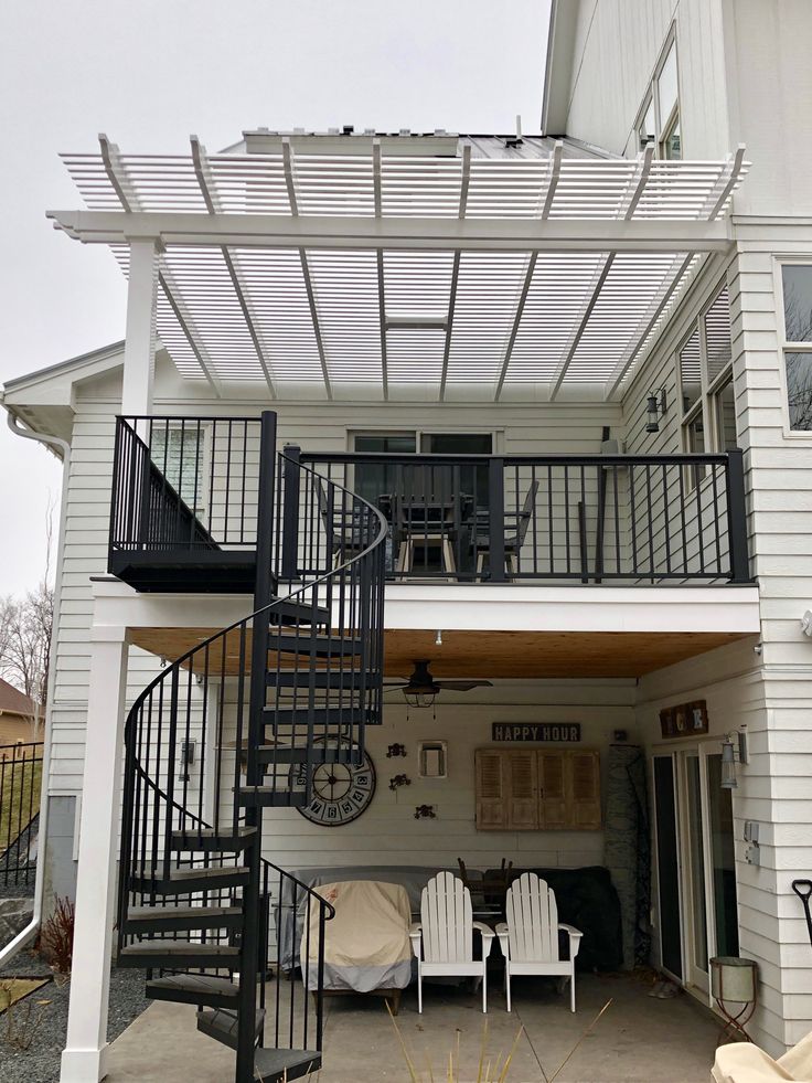 a white house with a black spiral stair case and patio furniture on the front porch