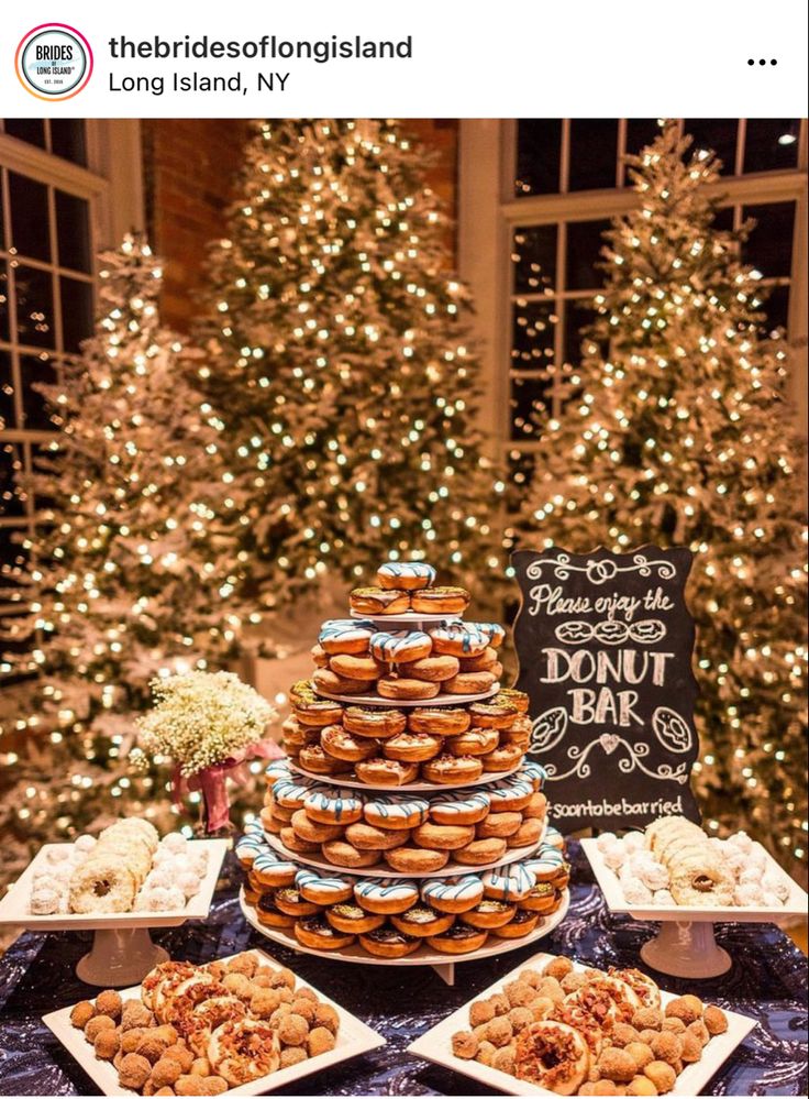 a table topped with lots of desserts next to a tree covered in christmas lights