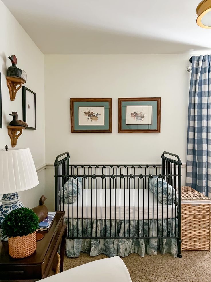 a baby's crib in the corner of a room with two pictures on the wall