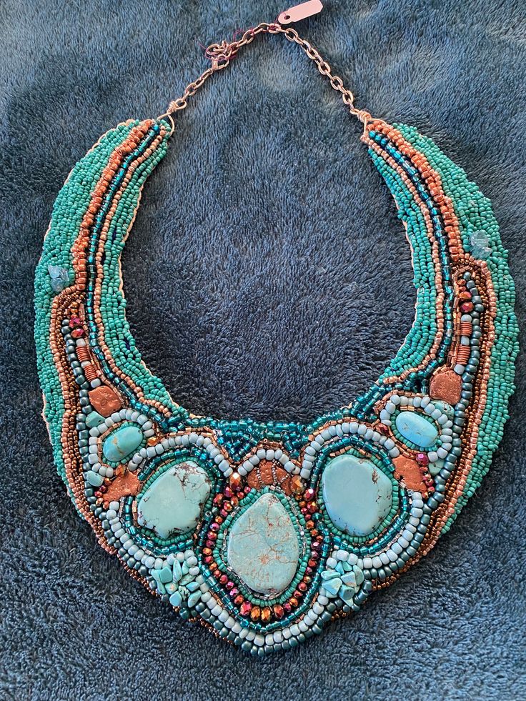 a multi - stranded necklace with turquoise and orange beads on a blue background,