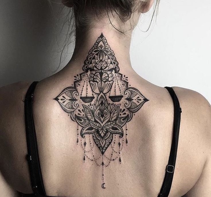 the back of a woman's neck with an intricate tattoo