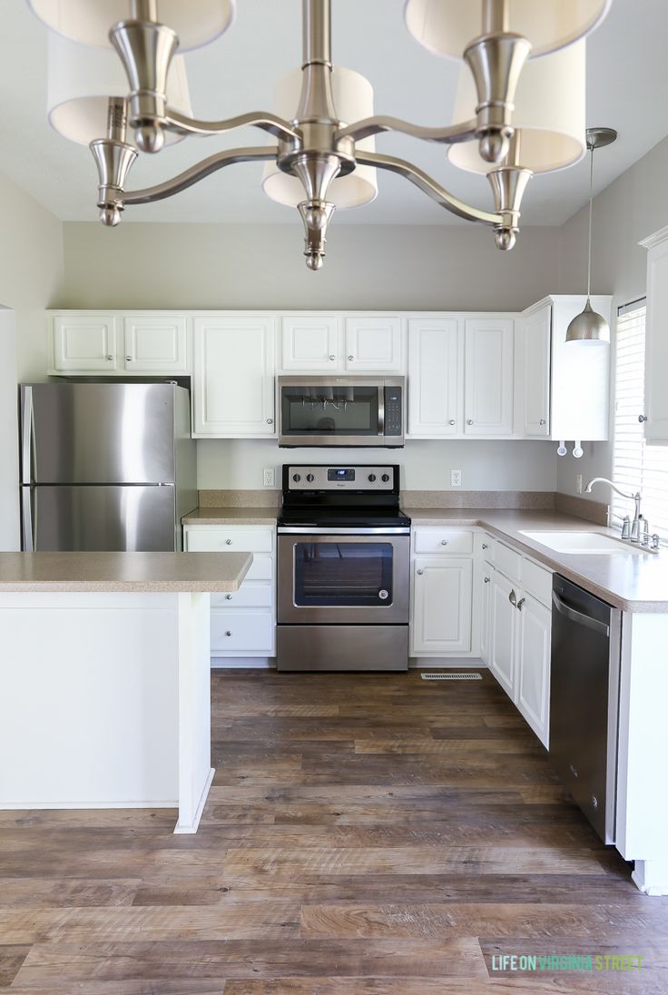 an empty kitchen with stainless steel appliances and white cabinets