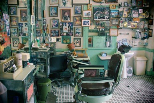 an old fashioned barber shop with lots of pictures on the wall and chairs in it