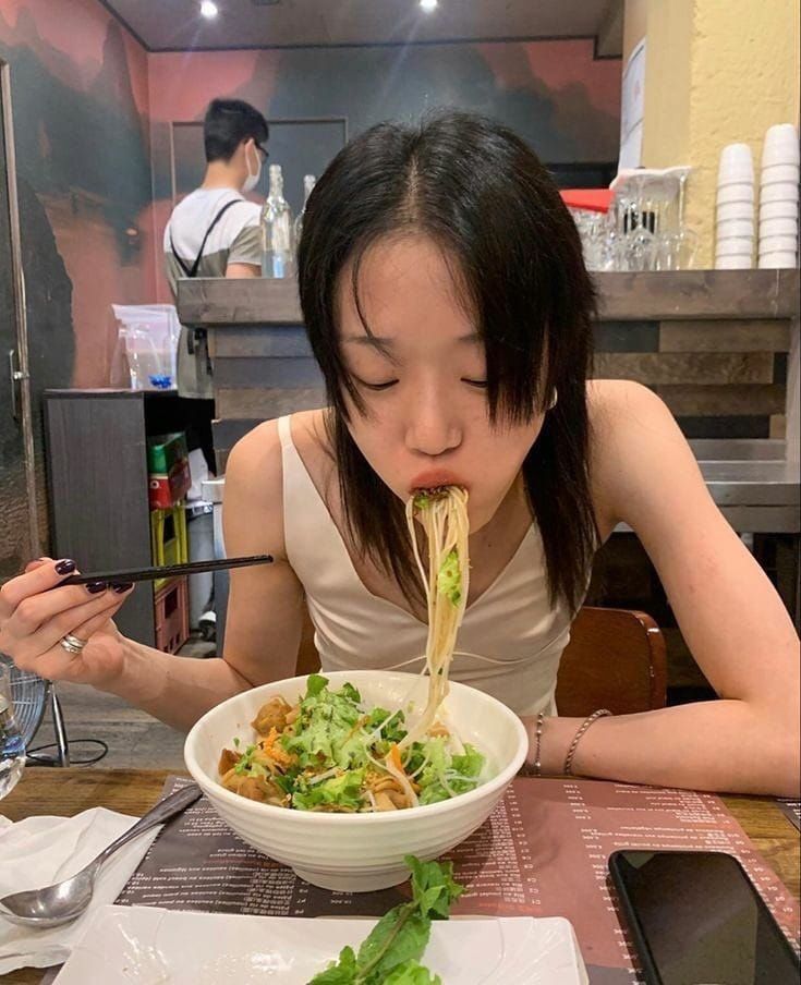 a woman sitting at a table with a bowl of food in front of her