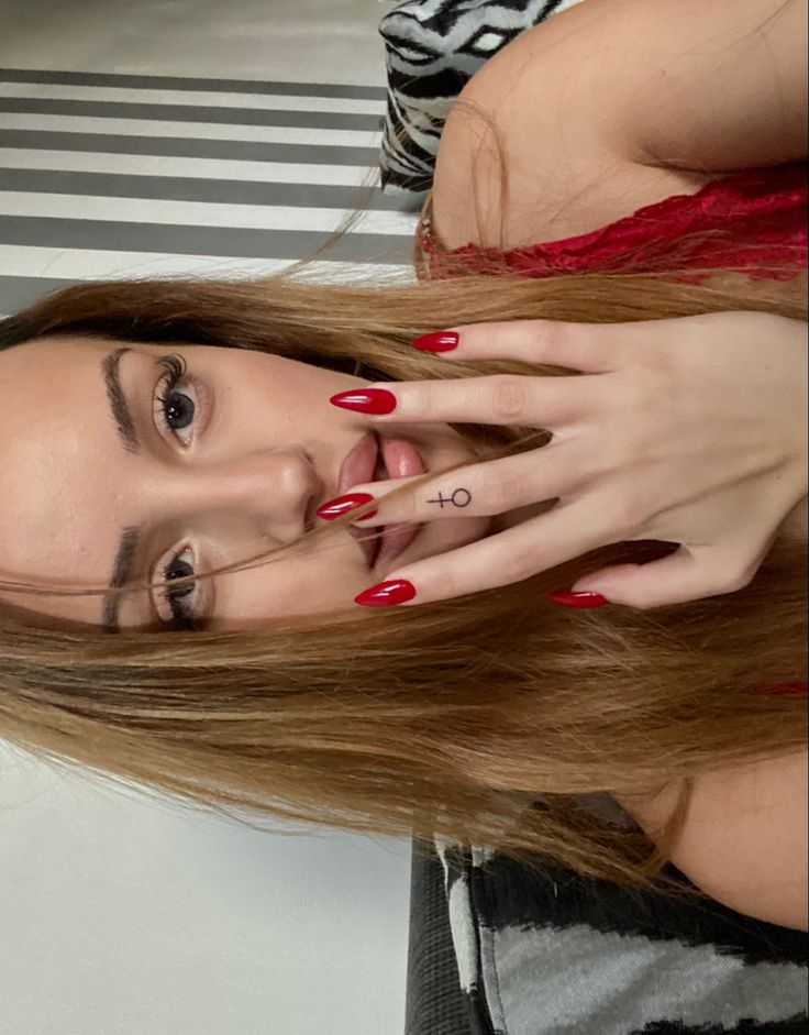 a woman with long red nails is posing for the camera